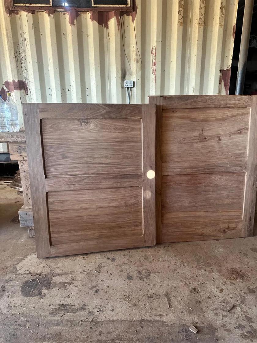 Two wooden panel doors leaning against a wall in the workshop