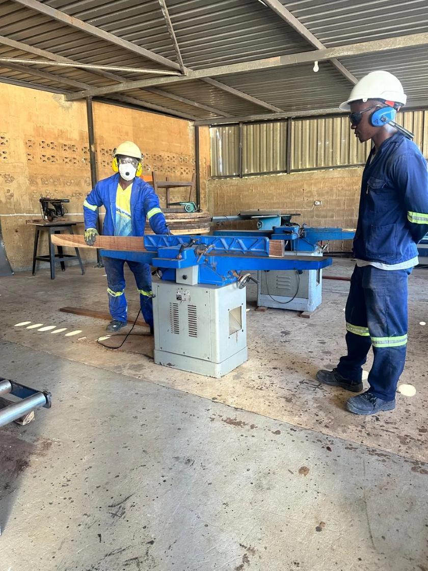 Two carpenters working at a planing machine in the SR Pr&aacute;tico workshop